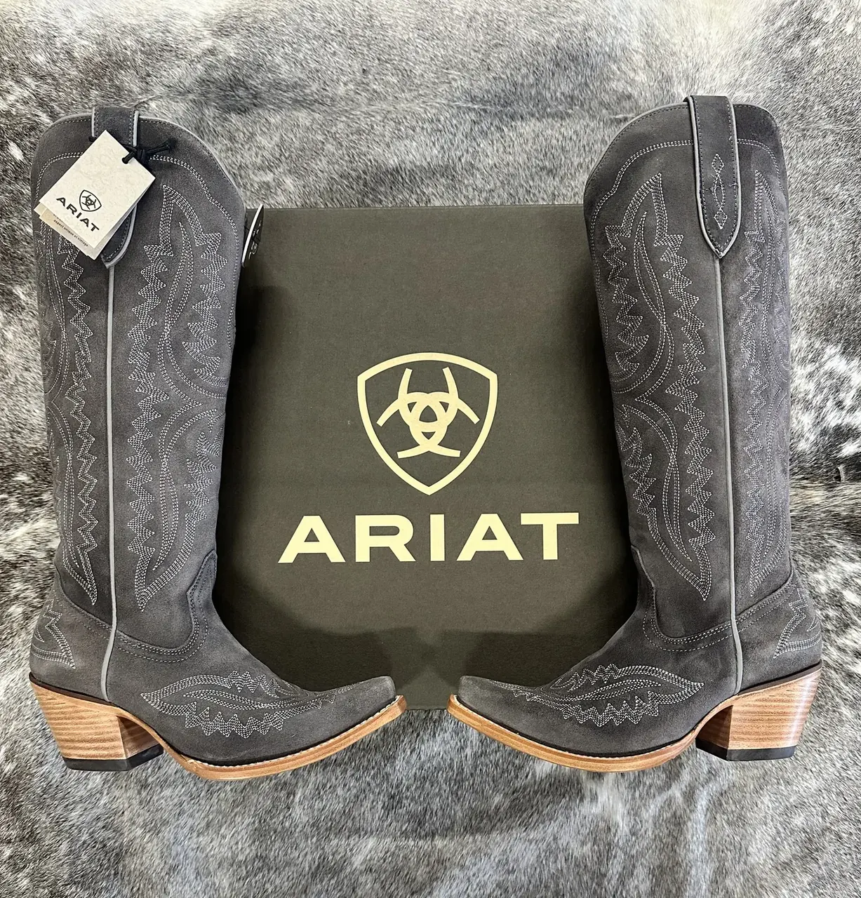 Gray Ariat western boots with Ariat box on cowhide