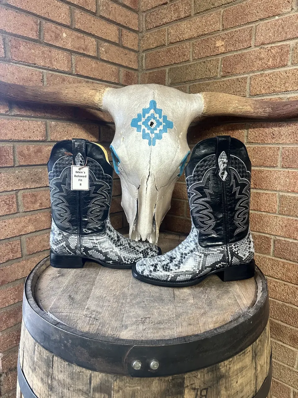 Black snake-print cowboy boots on a barrel with steer skull