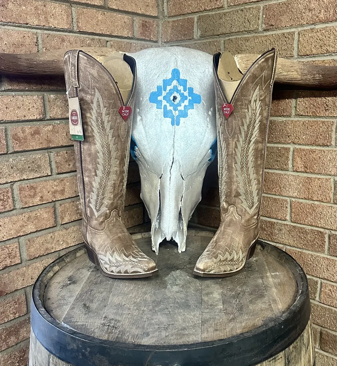 Light tooled cowboy boots on a barrel with steer skull