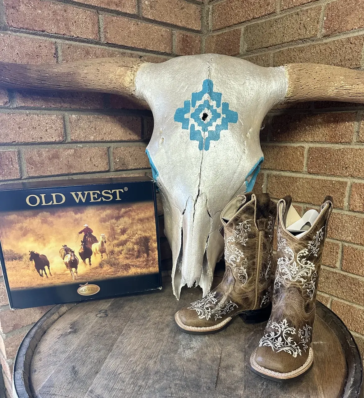 Old West cowboy boots displayed on a barrel with steer skull